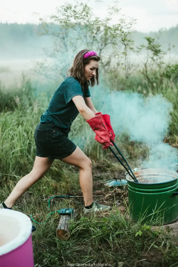 Wyjmowanie rozżarzonej ceramiki z pieca raku w dymie, podczas plenerowych warsztatów