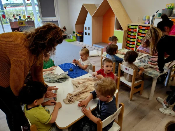 Przedszkolaki przy stolikach podczas warsztatów z gliną w przedszkolu